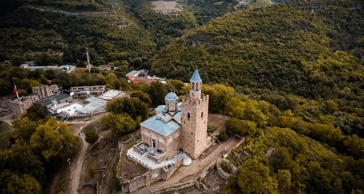 Vue aérienne d'une ancienne église en pierre entourée d'une forêt.