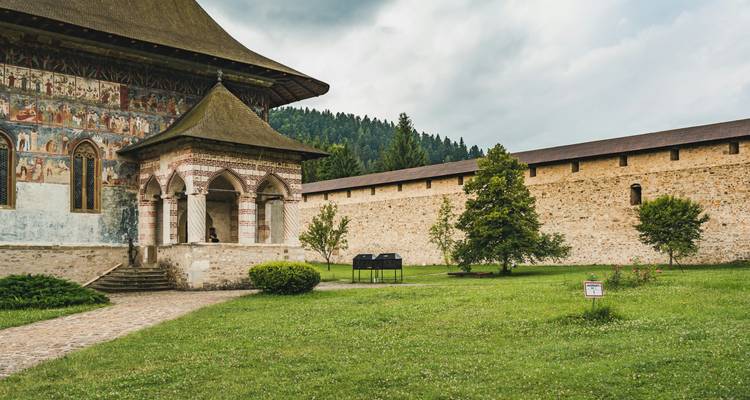 Monastère avec des fresques détaillées et des jardins luxuriants.