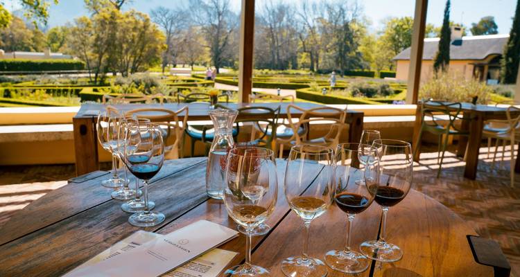 Table dressée for dégustation de vin sur une terrasse avec vue sur un jardin, sous un ciel dégagé.