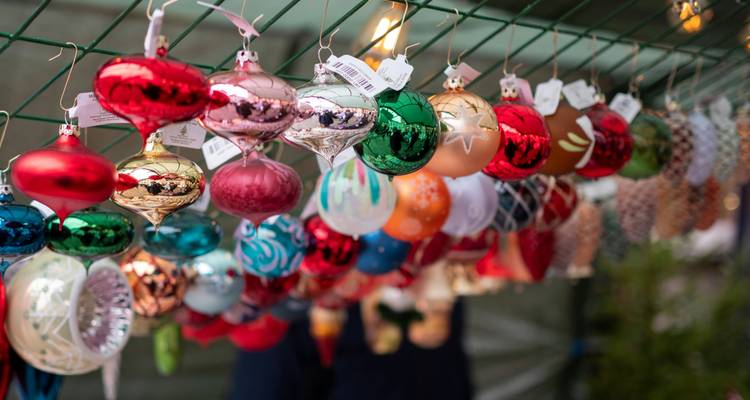 Des ornements de Noël colorés suspendus à la vente dans un étal de marché.