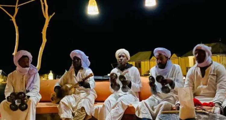 Músicos con atuendo tradicional tocando instrumentos por la noche.