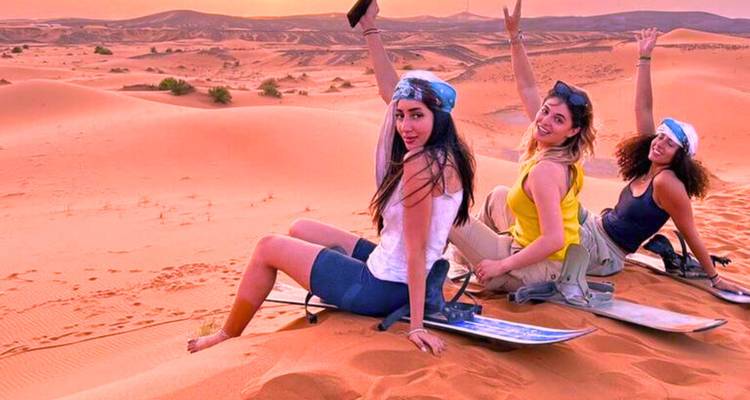 Grupo de mujeres haciendo sandboard en el desierto.
