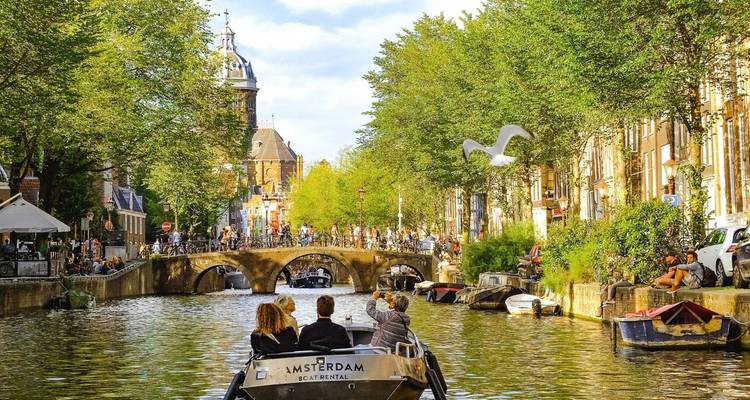 Un canal à Amsterdam avec des bateaux et des touristes.