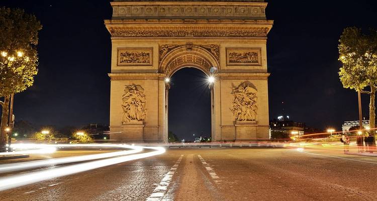 L'Arc de Triomphe à Paris, illuminé la nuit.