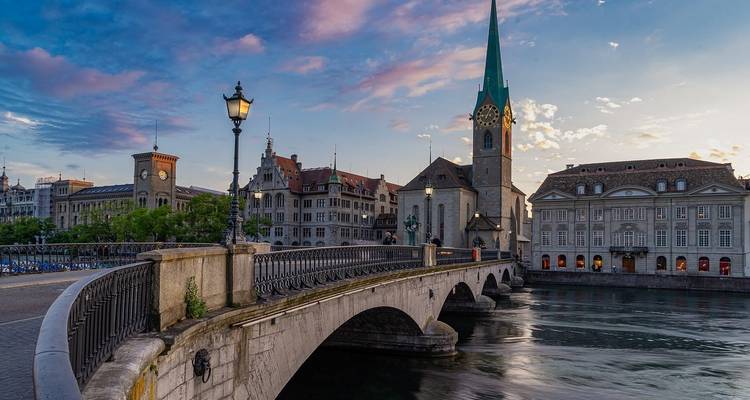 Un pont au-dessus d'une rivière dans une ville européenne au coucher du soleil.