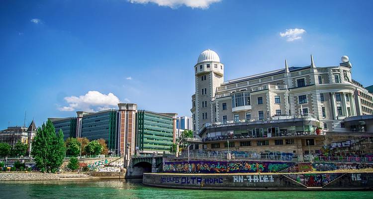 Bâtiments le long d'une rivière avec une architecture moderne et historique.