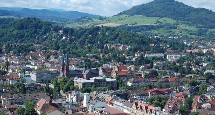 Vue aérienne d'une ville entourée de collines vertes et de montagnes.