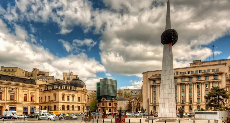 Une place de ville avec une sculpture moderne et des bâtiments historiques.