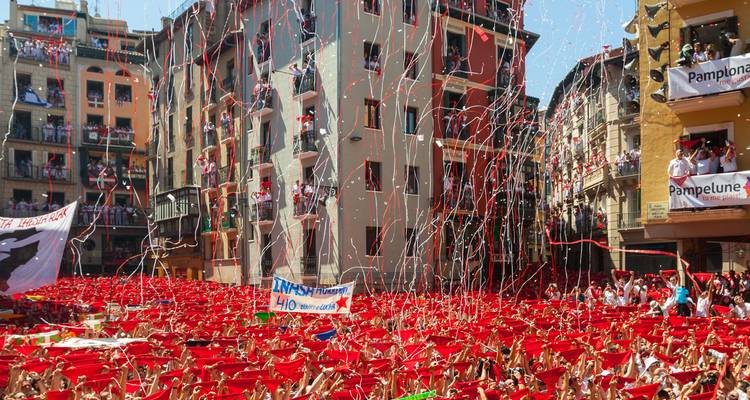 Messe de fêtards au foulard rouge célébrant le festival de San Fermín avec des confettis dans les rues de Pampelune