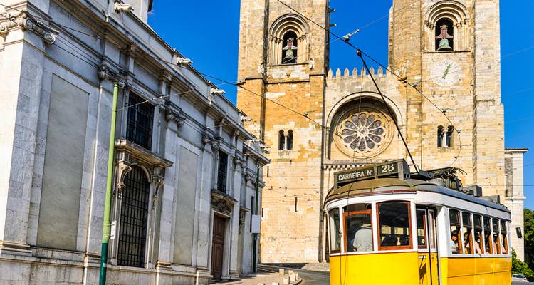 Tramway historique passant devant une cathédrale à Lisbonne.
