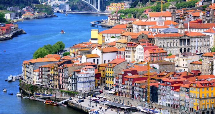 Vista panorámica de edificios coloridos a lo largo del río Duero con un puente al fondo.