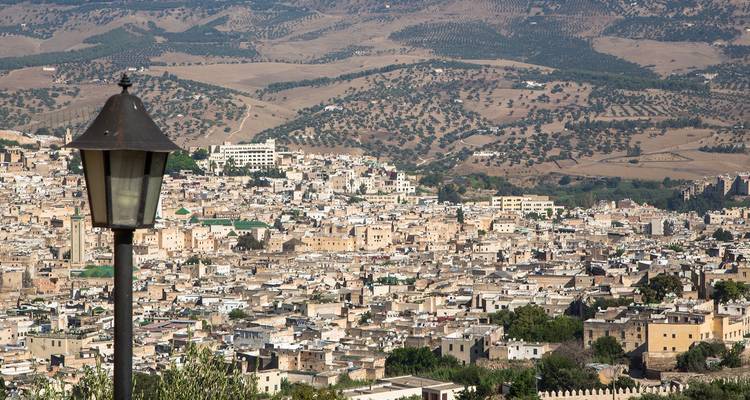 Panoramablick auf die Altstadt von Fes vom Hügel aus, eingerahmt durch traditionelle Straßenlampen