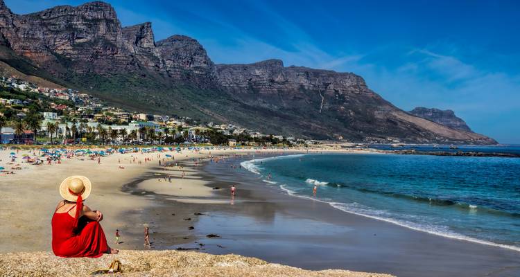 Vue côtière avec une femme en robe rouge et des vacanciers sur la plage