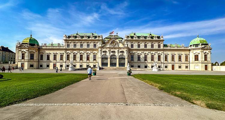 Palais historique avec un grand jardin et des gens qui se promènent.