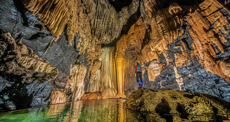 Persoon die een verlichte grot met prachtige formaties verkent.