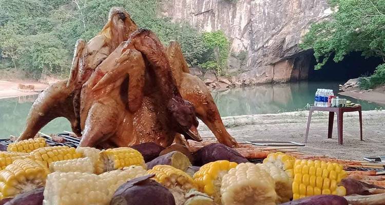 Barbecue voedseluitstalling met een grotingang op de achtergrond.