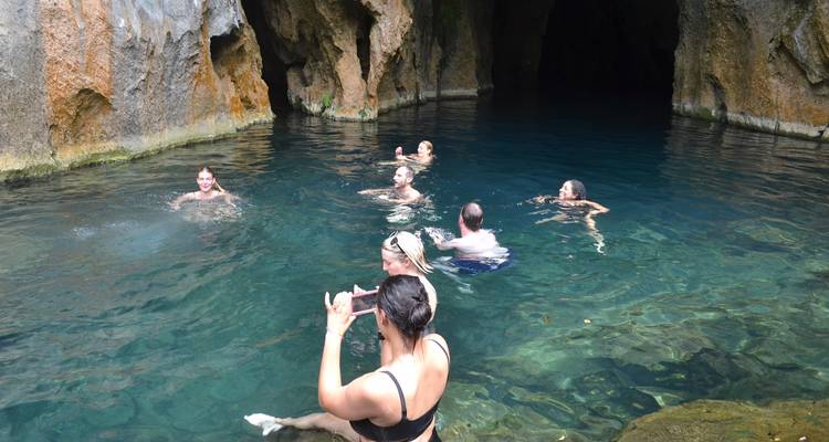 Mensen zwemmen in een helderblauw watergrotten zwembad.