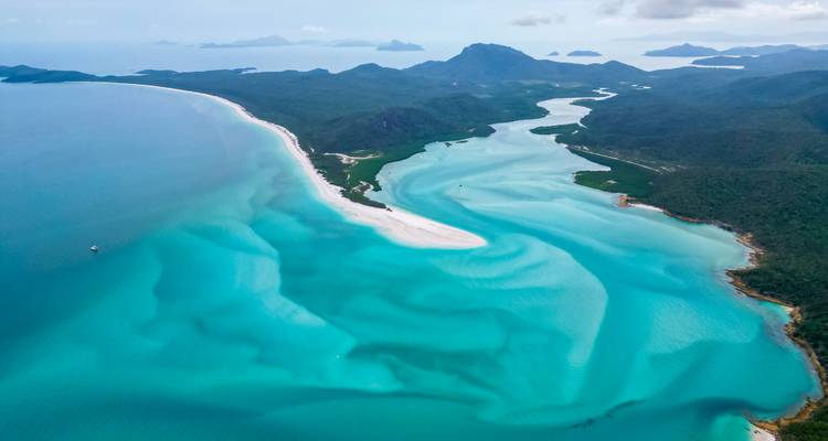 Luchtfoto van ongerept strand en kronkelende rivier met turquoise water.
