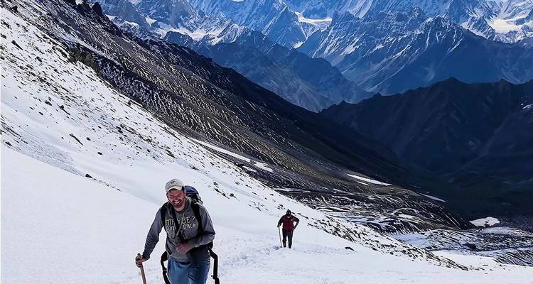 Deux personnes faisant de la randonnée sur une pente de montagne enneigée.