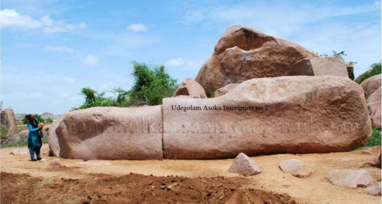Große Felsen mit Inschriften und eine Person, die daneben steht.