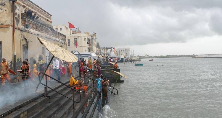 Menschen versammelten sich an Flusstreppen mit historischen Gebäuden, Dwarka, Indien.