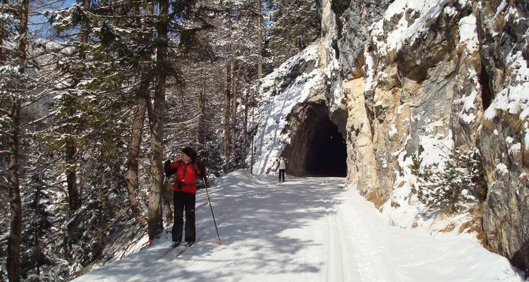 Personne skiant dans un tunnel sur un chemin enneigé.