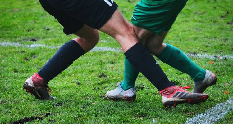 Primer plano de las piernas de los jugadores de fútbol entrelazadas en acción.