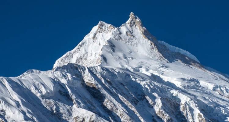 Sommet d'une montagne enneigée sous un ciel bleu limpide.