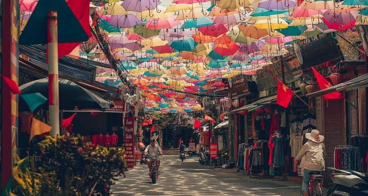 Des parapluies colorés suspendus au-dessus d'une rue avec des gens qui marchent.