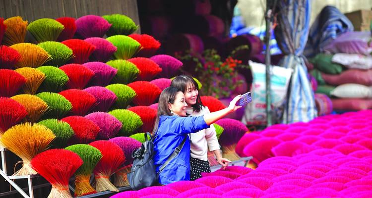 Deux femmes prenant un selfie devant des bâtons d'encens colorés.