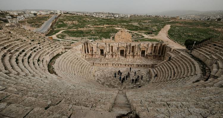 Amphithéâtre romain antique avec des gens qui explorent le site.