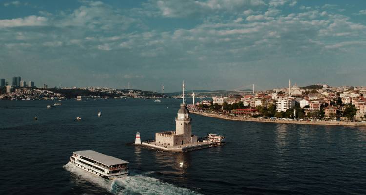Scène de front de mer avec un phare et un bateau dans un port animé.