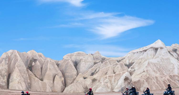 Des gens roulant sur des quads dans un paysage désertique rocheux.