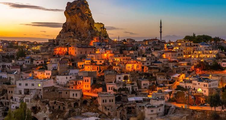 Une vue panoramique d'une ville construite sur un terrain rocheux sous la lumière du soir.