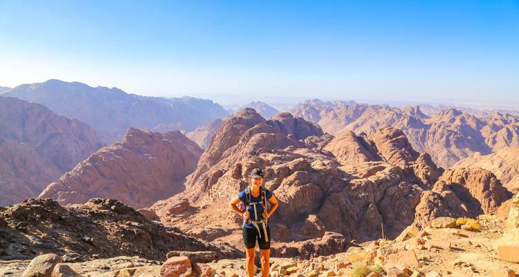 Excursionista de pie en una montaña con vista a un paisaje rocoso