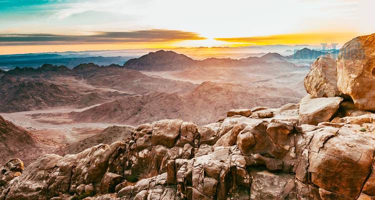 Vista panorámica de terreno rocoso al amanecer con montañas al fondo.