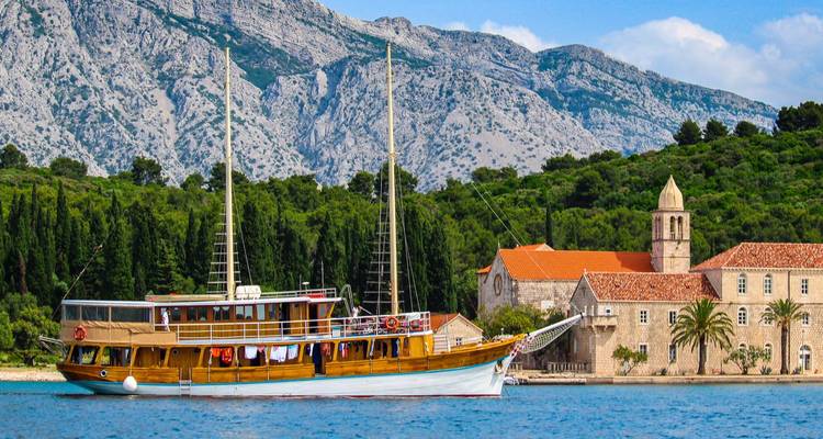 Bateau en bois près d'un bâtiment côtier avec une végétation luxuriante.