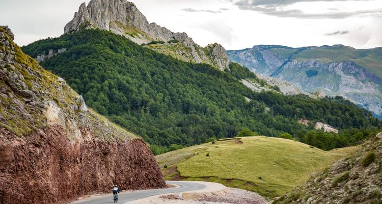 Eine malerische Straße mit einem Radfahrer inmitten hügeliger Landschaften.