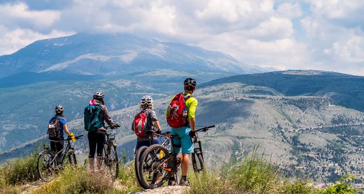 Gruppe von Mountainbikern mit Blick auf eine weite Berglandschaft.