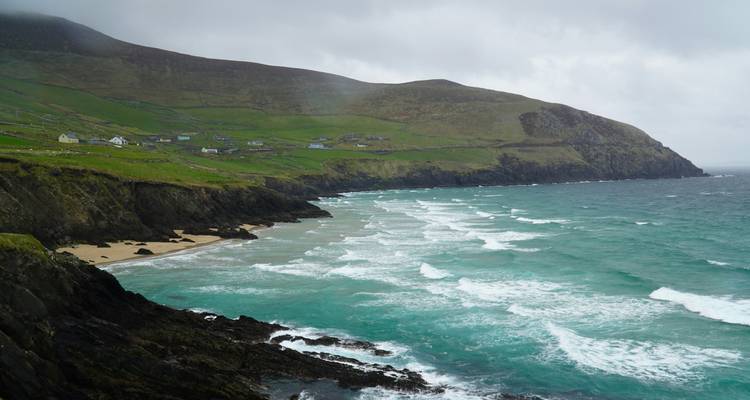 Coastal view with green cliffs and rolling waves.