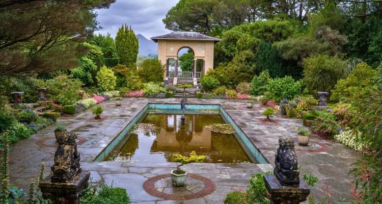 A formal Italian garden with a central reflecting pool, lush colourful flowerbeds and pavilion.