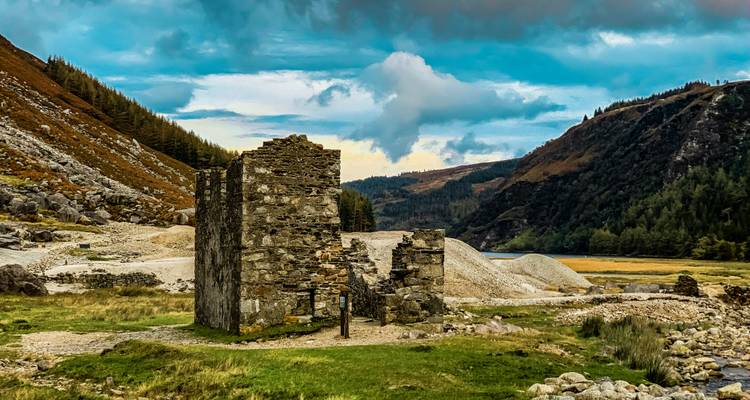 Ruines dans un paysage montagneux avec un ciel nuageux.