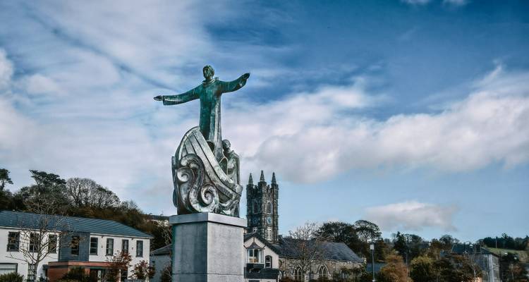 Une statue sur une petite place de ville avec une église en arrière-plan.
