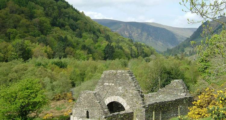 Ruins of a stone building nestled in a lush green valley.