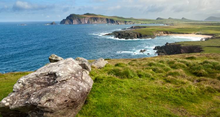 A scenic view of a rocky coast with grassy hills and cliffs meeting the ocean.