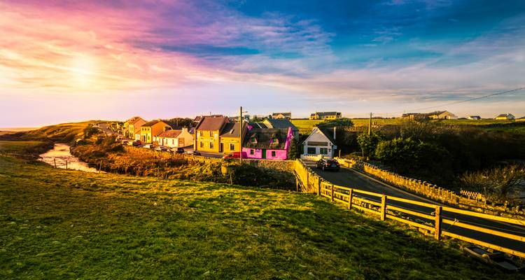 Colorful village houses with a river at sunset.