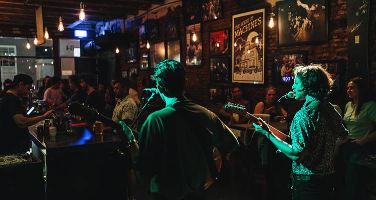 Livemusik-Auftritt in einer schwach beleuchteten, überfüllten Bar.