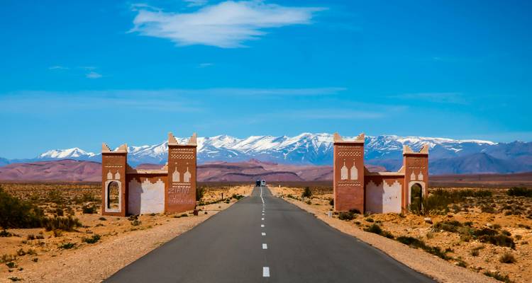 Road leading to mountains with traditional gate.