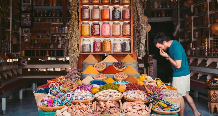 Market stall with colorful spices and a person smelling them.