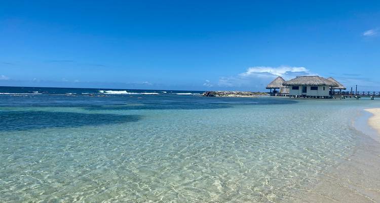 Idyllic beach with clear water and a cabana on the horizon.
